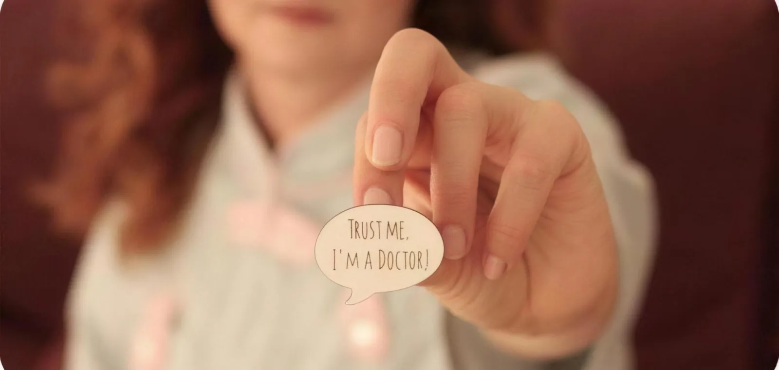 Женщина держит значок «Trust me, I'm a doctor»